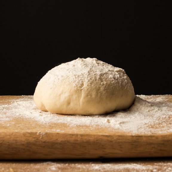 front-view-hand-sprinkling-flour-dough-cutting-board